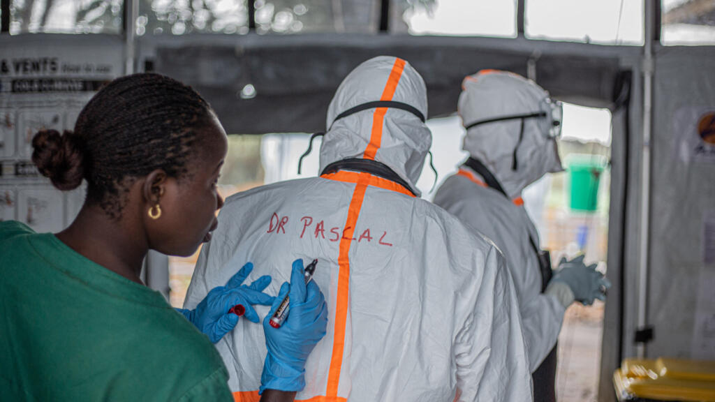 A hygiene agent marks a doctor's name on their personal protective equipment (PPE) before entering the Rwampara Ebola Treatment Center (ETC) to care for patients infected with Ebola virus disease in Bunia, Ituri, eastern Democratic Republic of Congo, on July 13, 2026.